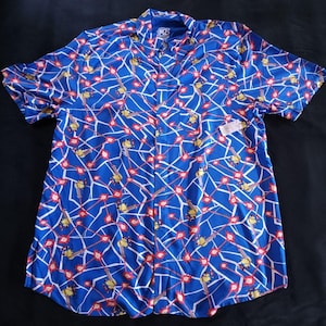 May include: A blue short-sleeved button-down shirt with a pattern of yellow cartoon characters and red laser beams. The shirt has a white collar and a button-up front.