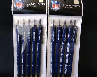 Puede incluir: Dos juegos de 5 bolígrafos retráctiles de los Seattle Seahawks. Los bolígrafos son de color azul marino con el logotipo del equipo y la palabra "SEAHAWKS" impresa. El embalaje incluye el logotipo de la NFL y las palabras "CLICK PENS 5-PACK".