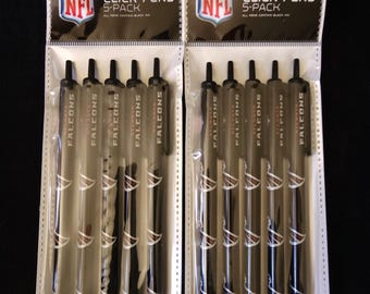 Puede incluir: Dos paquetes de bolígrafos de clic NFL Atlanta Falcons. Cada paquete contiene cinco bolígrafos. Los bolígrafos son negros con el logotipo y el texto de los Falcons. El embalaje incluye el logotipo de la NFL y las palabras "CLICK PENS 5-PACK".