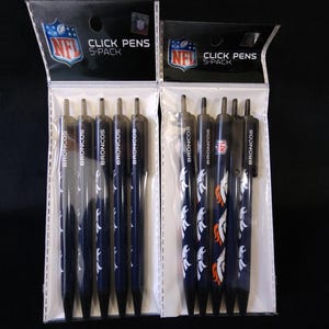 May include: Two 5-pack sets of click pens featuring the Denver Broncos NFL team logo. The pens are black with white and orange team graphics and the word "BRONCOS". The packaging includes the NFL logo.