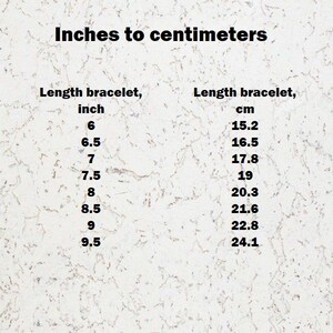 Op de afbeelding: Een conversietabel getiteld Inches to centimeters voor armbandlengtes. De linkerkolom toont waarden van 6 tot 9,5 inch en de rechterkolom geeft de bijbehorende metrische equivalenten van 15,2 tot 24,1 cm weer.