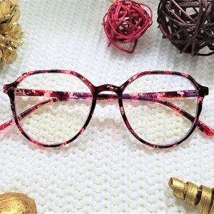May include: Red and black patterned eyeglasses with a round frame.