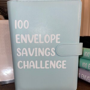 Desafío De Ahorro 100 Sobres ROSYLEVE - Carpeta A5 Con Sobres Numerados, 6 Subrayadores, Ahorra Hasta 5050€ En 100 Días, Color Lila