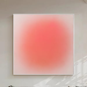 Könnte beinhalten: Ein quadratisches Wandbild mit einem weichen Verlaufseffekt, der von einem blassen, cremeweißen Außenrand zu einem leuchtenden, gesättigten korallenrosa Zentrum übergeht, eingefasst in einen dünnen, schlichten weißen Rahmen an einer neutralen Wand.