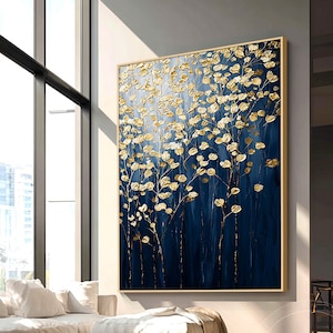 May include: Large abstract painting with gold leaf accents on a deep blue background. The artwork features stylized floral elements, creating a textured and dimensional effect. The painting is framed in a gold-colored wooden frame, suitable for home decor.
