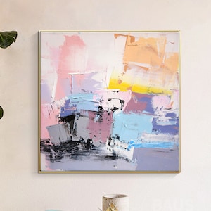 May include: Abstract painting with a gold frame. The painting features a colorful abstract design with shades of pink, blue, yellow, and gray.