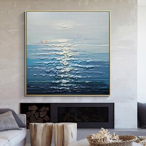 May include: Abstract painting of a seascape with blue and white waves and a light blue sky. The painting is framed in a gold frame.