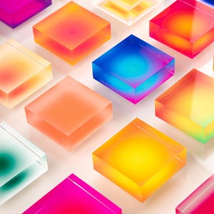 Puede incluir: Una serie de bloques cuadrados transl&uacute;cidos y coloridos en varios tonos de rosa, naranja, amarillo, azul y verde. Los bloques est&aacute;n dispuestos en un patr&oacute;n de cuadr&iacute;cula, creando una exhibici&oacute;n vibrante. Los bloques parecen estar hechos de un material transparente.