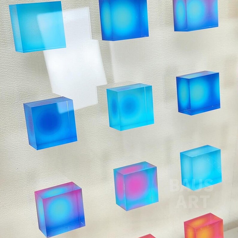 May include: A wall display of 10 small, square, clear resin blocks with a blue, pink, or orange gradient. The blocks are arranged in a grid pattern.