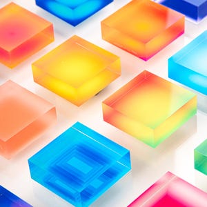 Puede incluir: Una matriz de bloques cuadrados transl&uacute;cidos y coloridos en tonos de azul, naranja, amarillo, rosa y verde. Los bloques est&aacute;n dispuestos en un patr&oacute;n de cuadr&iacute;cula, con algunos bloques que tienen un dise&ntilde;o interior en capas.