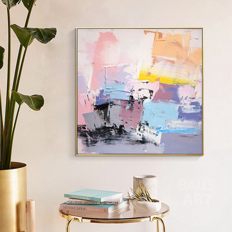 May include: Abstract painting with a gold frame. The painting features a colorful abstract design with shades of pink, blue, yellow, and gray.