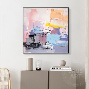 May include: Abstract painting with a colorful palette of pink, blue, yellow, and gray. The painting is done in a loose, gestural style with thick brushstrokes.