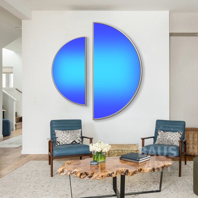 May include: Two semi-circular wall art pieces featuring a vibrant blue gradient, transitioning from a deep royal blue at the outer edges to a bright cyan in the centre, each enclosed within a thin, metallic silver frame mounted on a white wall.