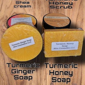 Könnte beinhalten: Vier Produkte von Afro Cosmetics LLC: Kurkuma-Sheabutter-Creme, Kurkuma-Honig-Peeling, Kurkuma-Ingwer-Seife und Kurkuma-Honig-Seife. Die Produkte werden auf einer Holzoberfläche präsentiert.