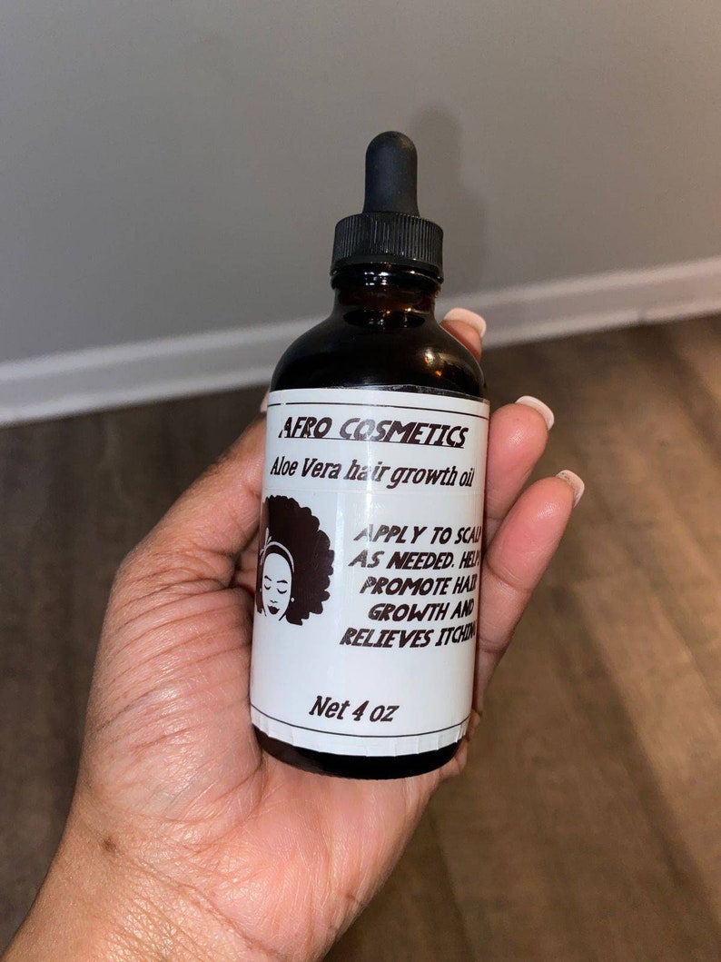 Puede incluir: Una botella de vidrio transparente con un gotero negro y una etiqueta blanca. La etiqueta dice "AFRO COSMETICS Aceite de crecimiento del cabello de Aloe Vera" e incluye instrucciones de uso. La botella contiene 118 ml de producto.