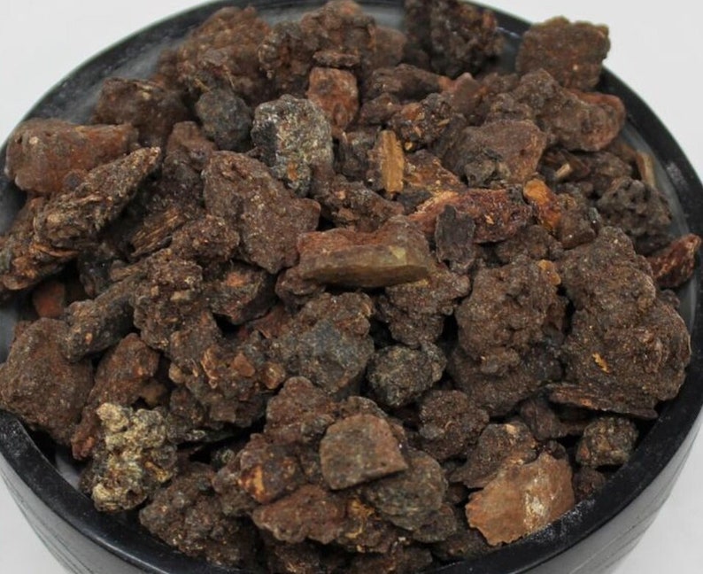 May include: Close-up of a pile of dark brown and black resinous chunks. The resin is irregularly shaped and has a rough texture.