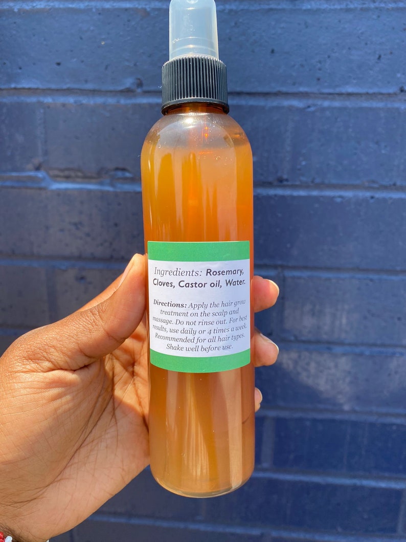May include: A brown glass bottle with a green label that reads "Ingredients: Rosemary, Cloves, Castor oil, Water. Directions: Apply the hair grow treatment on the scalp and massage. Do not rinse out. For best results, use daily or 4 times a week. Recommended for all hair types. Shake well before use."