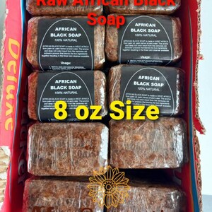Puede incluir: Ocho barras de jab&oacute;n negro africano crudo, cada una envuelta en pl&aacute;stico transparente, est&aacute;n dispuestas en una caja de cart&oacute;n. El jab&oacute;n es marr&oacute;n y tiene una textura natural y terrosa. La caja est&aacute; etiquetada como "Deluxe Tucker" y "Afro Cosmetics". El jab&oacute;n es de 8 onzas.