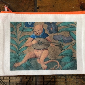 Könnte beinhalten: Weiße Canvas-Reißverschlusstasche mit orangefarbenem Reißverschluss und Besatz. Die Tasche zeigt eine Illustration im Renaissance-Stil einer Kreatur, die eine Laute spielt. Die Illustration ist vor einem Hintergrund aus blauem, grünem und braunem Laub angeordnet.