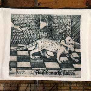 May include: A black and white vintage print of a cat catching a mouse. The print is on a white canvas pouch with a black zipper. The text "1577. Fleisch macht fleisch." is printed below the image.