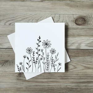 Cute and simple ink flowers on a white card sitting on a wooden table