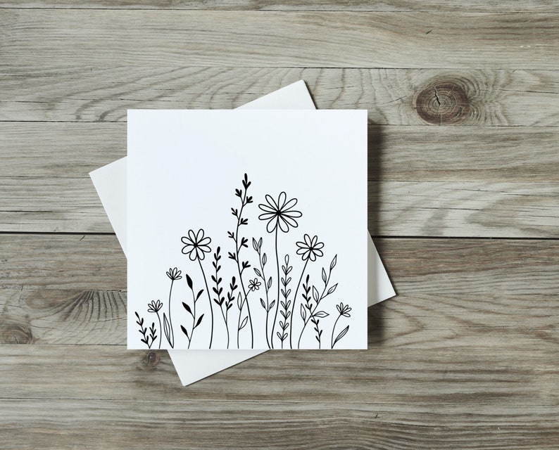 Cute and simple ink flowers on a white card sitting on a wooden table