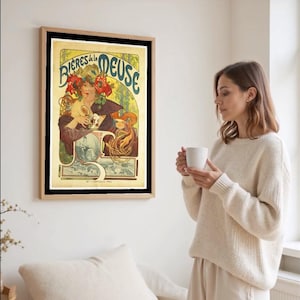 May include: A framed vintage poster with the text "Bieres de la Meuse" in blue and gold lettering. The artwork features a woman with red flowers in her hair, holding a glass. The poster is in a wooden frame.