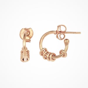 May include: A pair of gold-toned hoop earrings with a twisted design. The earrings are small and delicate.