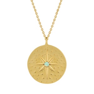 May include: Gold necklace with a round pendant featuring a starburst design with a light blue opal in the center.