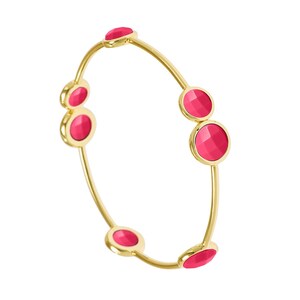 May include: A gold bangle bracelet with five pink round stones. The stones are set in the metal and are evenly spaced around the bracelet.