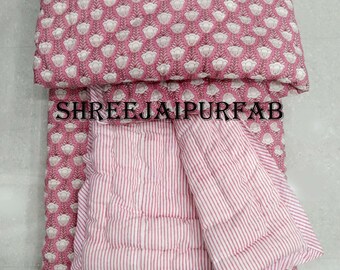 May include: Pink and white cotton quilt with a floral print on one side and white stripes on the other side. The quilt is folded in half and the text "SHREE JAIPUR FAB" is visible on the floral side.