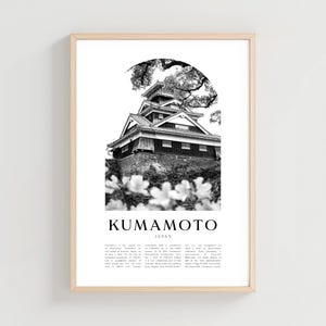 May include: Black and white framed print of Kumamoto Castle in Japan. The image features the castle, a traditional Japanese structure, with text that reads "Kumamoto Japan". The print is in a light wood frame.