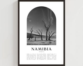 May include: Black and white framed print featuring a desert landscape with dead trees under an arched sky. The word "NAMIBIA" is printed in bold letters, with "AFRICA" below it. The print has a minimalist aesthetic.