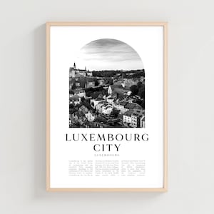 May include: Monochrome framed print of Luxembourg City. The image shows a cityscape with buildings and a castle under a semi-circular sky. The text "LUXEMBOURG CITY" is displayed below the image.