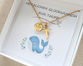 May include: A gold-toned necklace featuring a small cross pendant and a circular charm engraved with the name Lina and a heart symbol. The necklace is presented on a white card with a blue whale illustration and the text HERZLICHEN GLÜCKWUNSCH ZUR TAUFE.