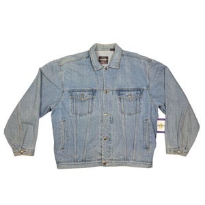 May include: Light blue denim jacket with button closures, two chest pockets, and two side pockets. The jacket has a classic collar and long sleeves with buttoned cuffs. A tag is attached to the jacket.