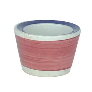 Puede incluir: Un pequeño cuenco de cerámica con interior blanco y exterior rojo con pinceladas horizontales. El borde es blanco con un borde azul. El cuenco se utiliza probablemente para servir salsas o pequeñas porciones de comida.