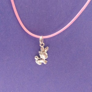 Op de afbeelding: Een roze koordketting met een zilveren bedel van een konijn met een bloem op zijn hoofd.