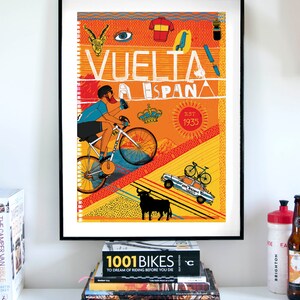 Op de afbeelding: Een kleurrijke poster met een fietser die bergop fietst. De poster bevat de tekst "VUELTA A ESPANA EST 1935" en verschillende illustraties, waaronder een stier, een kroon, een trui en een vogel.