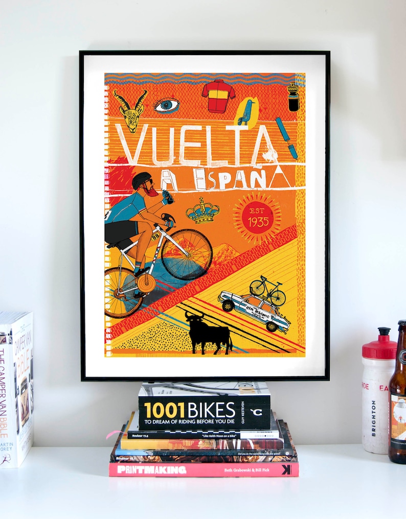 Op de afbeelding: Een kleurrijke poster met een fietser die bergop fietst. De poster bevat de tekst "VUELTA A ESPANA EST 1935" en verschillende illustraties, waaronder een stier, een kroon, een trui en een vogel.