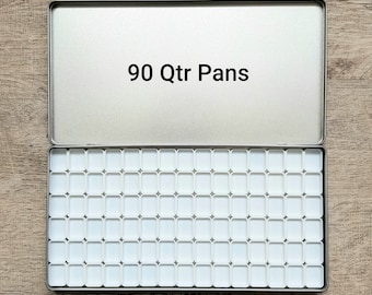 May include: An open, rectangular, silver-colored metal tin with 90 white quarter pans. The lid is open, revealing the interior filled with the empty pans. The text "90 Qtr Pans" is printed in black on the inside of the lid.