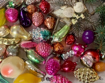 May include: A selection of vintage Christmas tree decorations in the form of fruits and vegetables. The glass baubles are in various colours and finishes, including shiny, frosted, and glittered. Some have silver and white accents. A festive assortment.