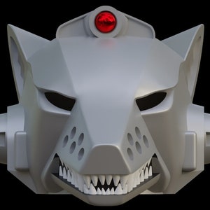 Puede incluir: Una máscara de lobo plateada con una luz roja en la parte superior. La máscara tiene un hocico afilado con dientes y ojos negros.