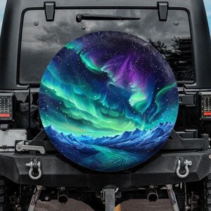 May include: A black Jeep with a spare tire cover featuring a vibrant depiction of the Aurora Borealis. The artwork showcases swirling green, blue, and purple lights over a mountainous landscape, set against a starry sky.