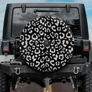 May include: Black Jeep with a spare tire cover featuring a white and black leopard print design.