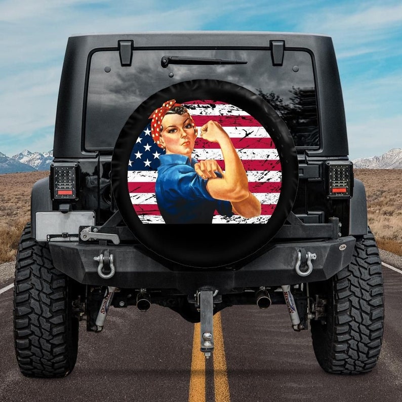 May include: A black Jeep with a spare tire cover featuring a vintage illustration of a woman with her arm raised in a 'We Can Do It' pose, superimposed on an American flag with a distressed look.