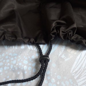 May include: Black drawstring bag with a black cord and a black plastic toggle.
