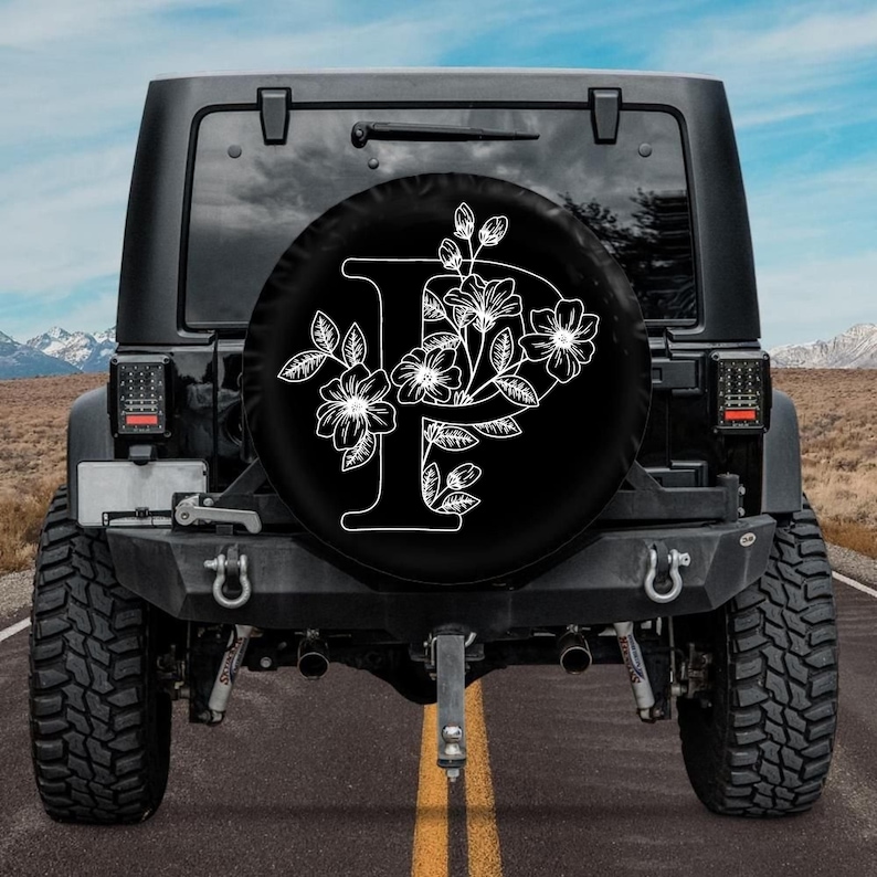 May include: A black Jeep with a spare tire cover featuring a white floral design with the letter "P" in the center.