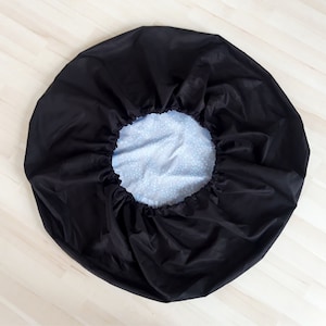May include: A black drawstring bag with a white and blue patterned lining. The bag is gathered at the top and has a drawstring closure.