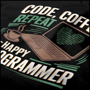 May include: A black t-shirt with green and white text that reads "CODE, COFFEE REPEAT - HAPPY GRAMMER". The text is styled with a retro font. A brown laptop with a green screen displaying binary code is shown in the background.